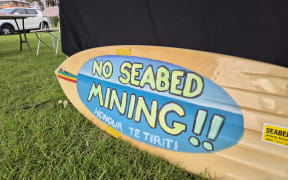 surfboard with 'no seabed mining' written on it