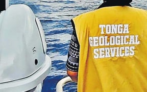 A scientist from the Tonga Geological Services watches the eruption of the volcano from a boat.