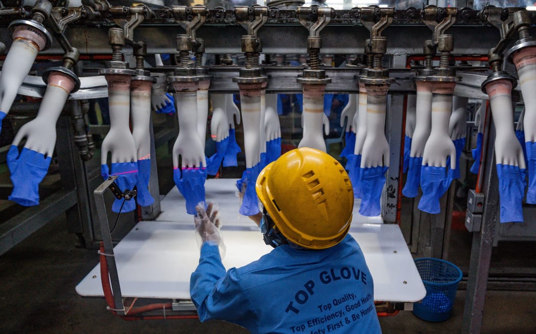 A worker inspects disposable gloves at the Top Glove factory production line in Shah Alam on the outskirts of Kuala Lumpur on August 26, 2020.
