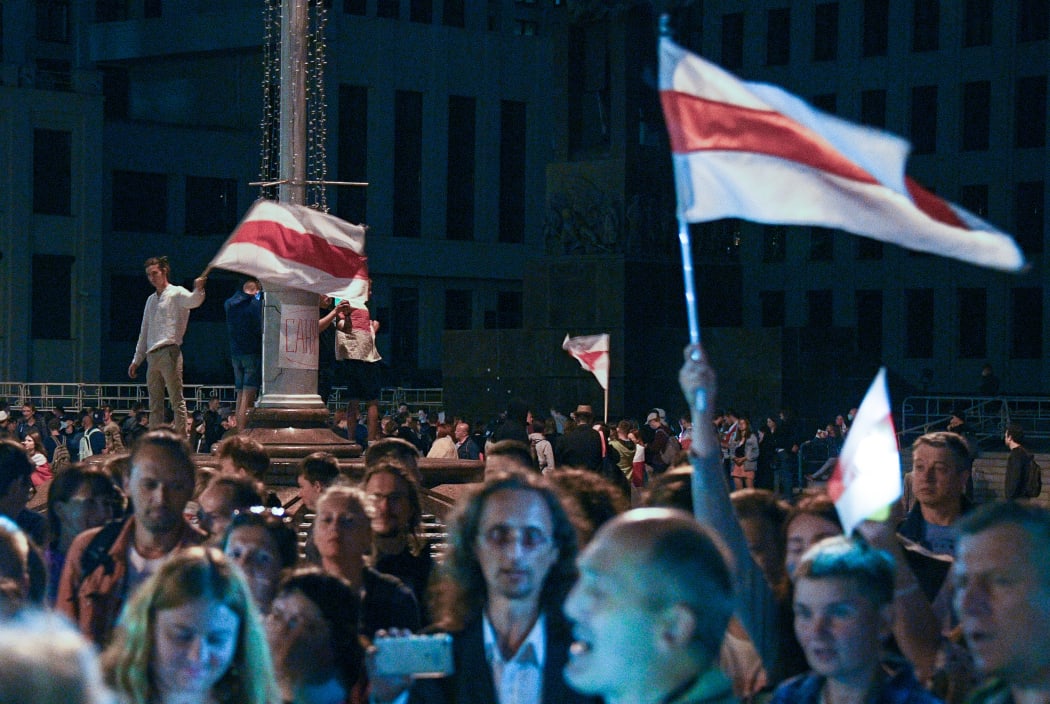 People hold flags as they take part in a demonstration against police violence following recent protests to reject the presidential election results, in Minsk, Belarus.