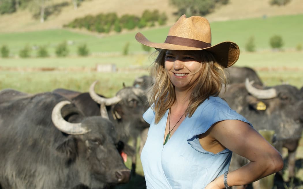 Helen Dorresteyn stands in an idyllic farm scene wearing a cowboy hat