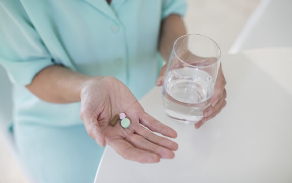 Senior woman taking vitamins with water. (Photo by CAIA IMAGE/SCIENCE PHOTO LIBRARY / NEW / Science Photo Library via AFP)