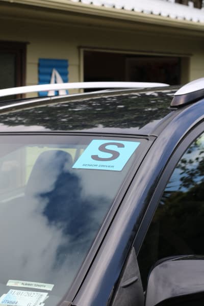 S sticker displayed on the front windshield of a car.