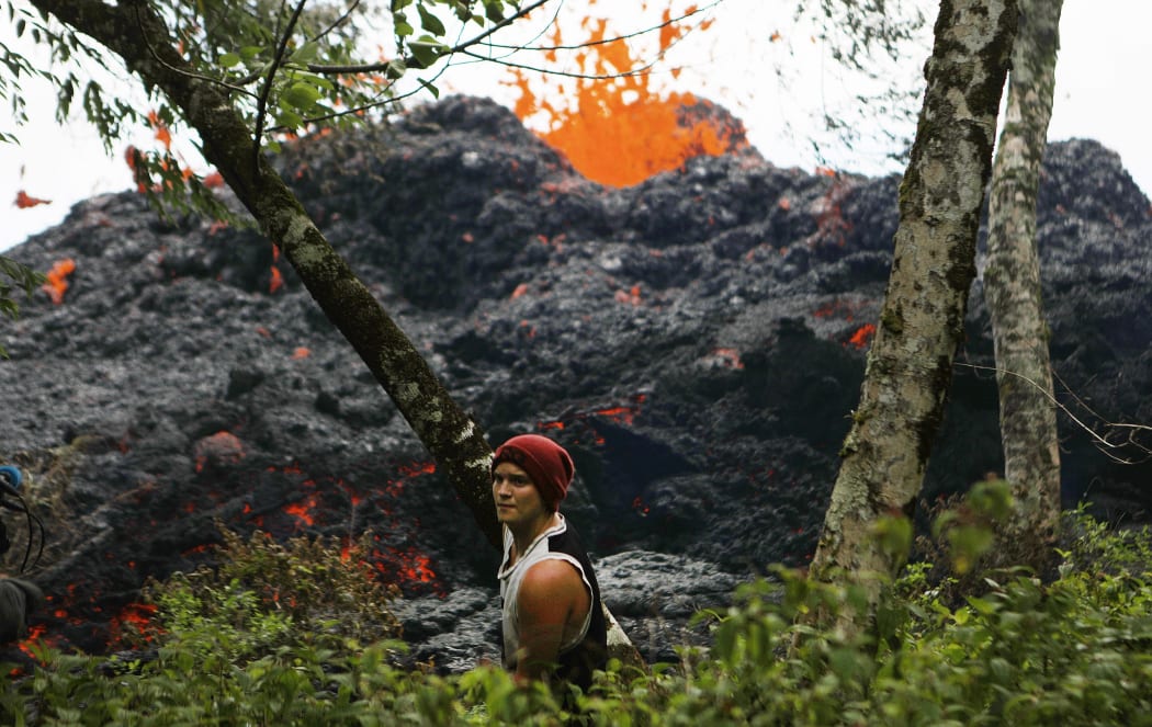 A lava fissure erupts as a resident stands nearby