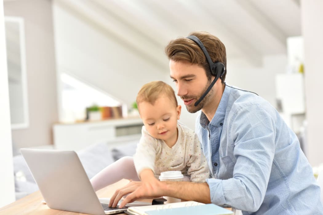 A photo of a busy businessman working from home and watching baby