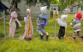 A school fence line covered in handmade scarecrows.