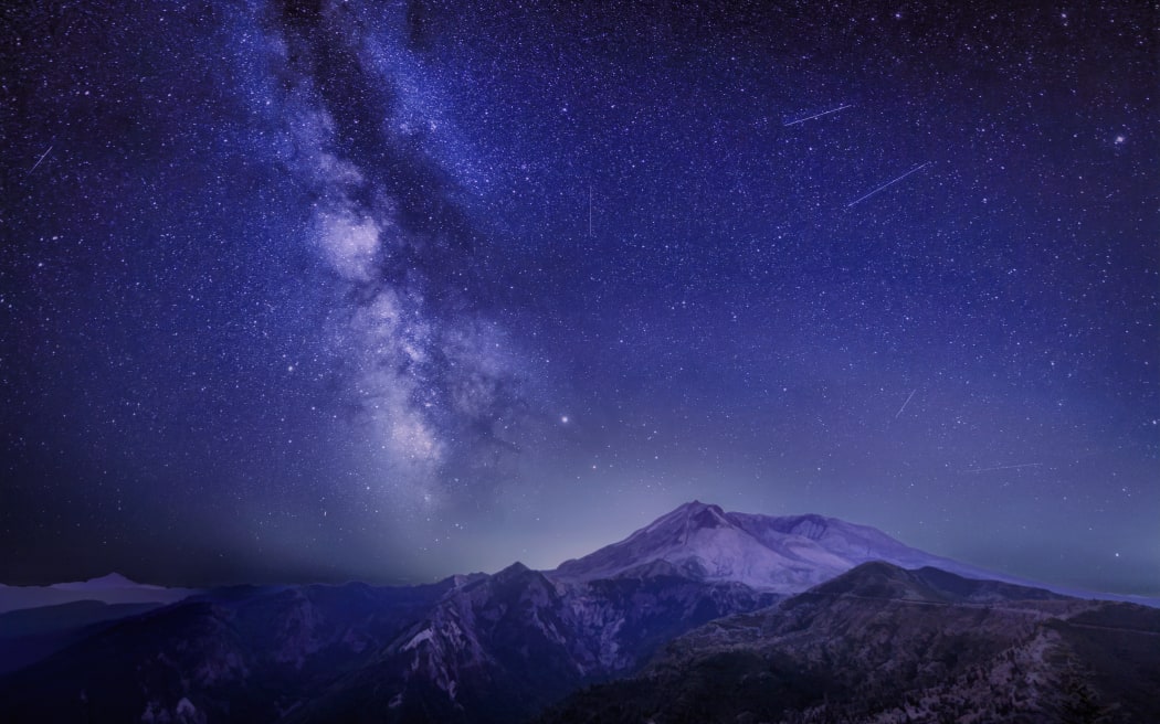 The Delta Aquariids meteor shower and Milky Way over Mount St. Helens, at Windy Ridge in Washington State with Mt. Hood, Oregon visible in the lower left corner. Portland, Oregon is fifty miles to the south as you can tell by the ambient light behind Mount St. Helens.