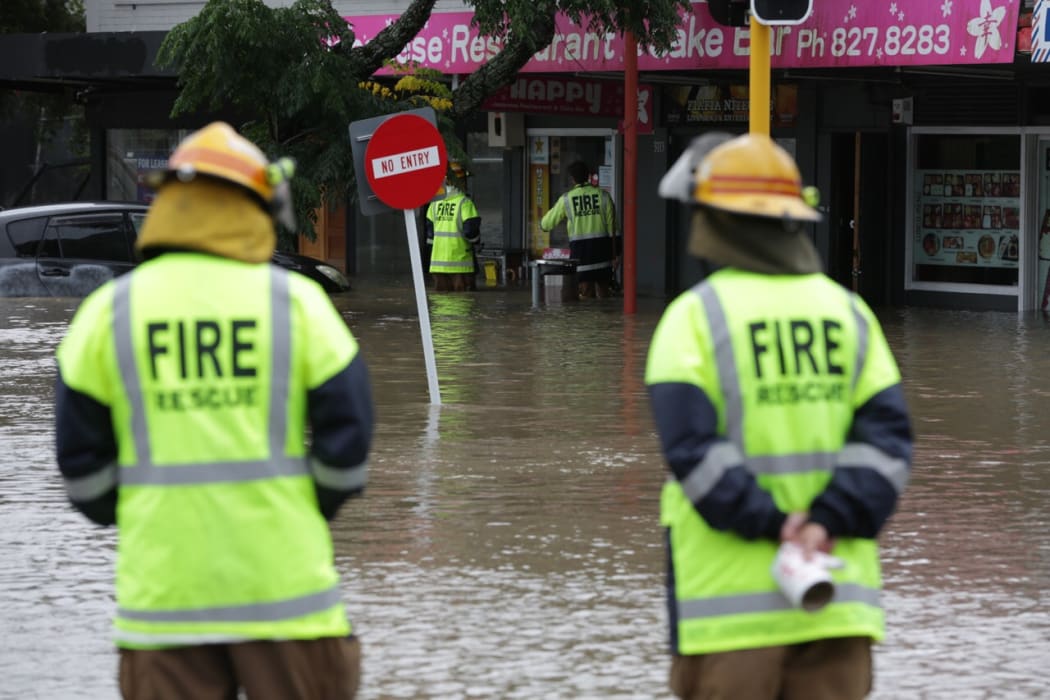 Firefighters check shops for people trapped in floodwaters in the west Auckland suburb of New Lynn.