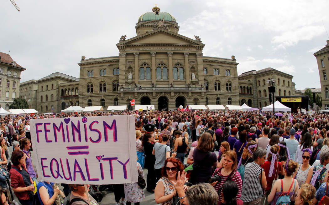 A woman holds a sign reading "Feminism = Equality" as she takes part in a nation-wide women's strike for wage parity outside the federal palace in Switzerland.