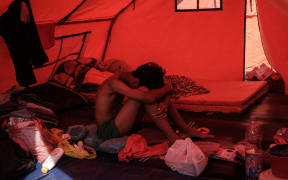 A young man rests in a makeshift shelter built for evacuees affected by a flash flood in Aceh Tamiang, Northern Sumatra, on December 13, 2025. Devastating floods and landslides have killed 1,006 people in Indonesia, rescuers said December 13 as the Southeast Asian nation grapples with the huge scale of relief efforts. (Photo by Yasuyoshi CHIBA / AFP)