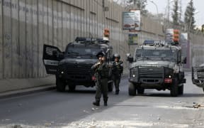 Israeli borderguards walk in front of military vehicles during clashes with Palestinian youth in the Palestinian village of al-Ram, between Jerusalem and Ramallah in the Israeli occupied West Bank, on October 22, 2015.