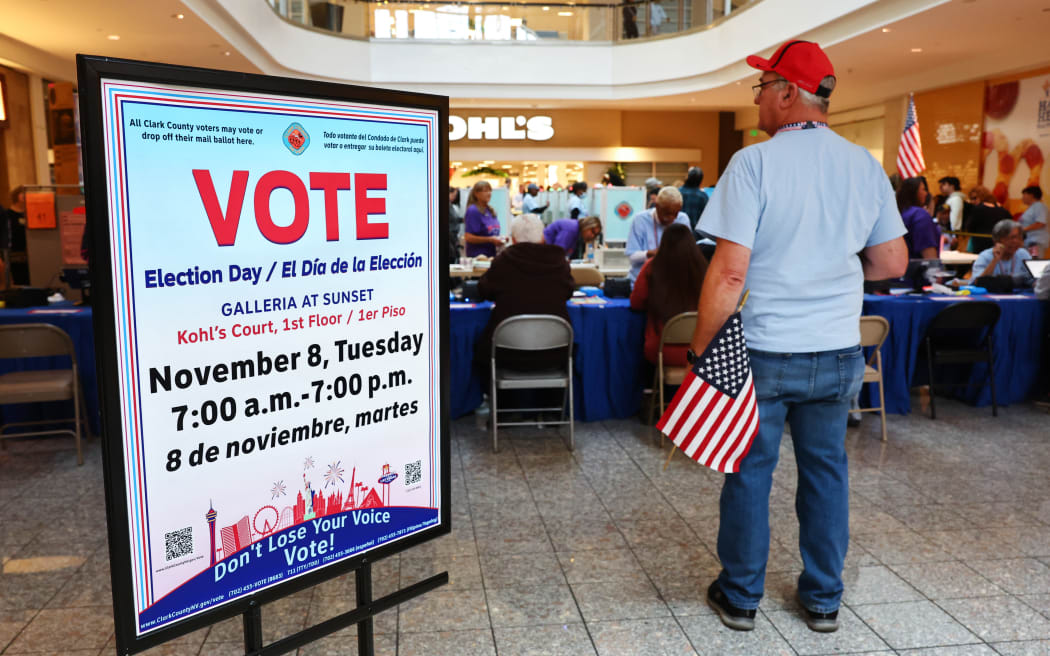 HENDERSON, NEVADA - NOVEMBER 08: An election worker holds an American flag at a polling place at Galleria at Sunset on November 08, 2022 in Henderson, Nevada. After months of candidates campaigning, Americans are voting in the midterm elections to decide close races across the nation.   Mario Tama/Getty Images/AFP (Photo by MARIO TAMA / GETTY IMAGES NORTH AMERICA / Getty Images via AFP)