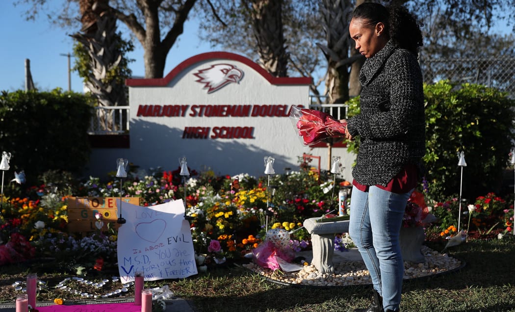 PARKLAND, FLORIDA - FEBRUARY 14: Sheena Billups prepares to lay flowers in a memorial setup at Marjory Stoneman Douglas High School for those killed during a mass shooting on February 14, 2019 in Parkland, Florida.