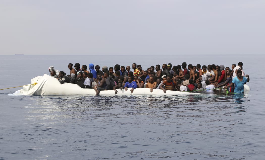 A file photo shows people waiting to be rescued from a sinking dinghy off the Libyan coastal town of Zawiyah, east of the capital, on 20 March, 2017, as they attempted to cross from the Mediterranean to Europe.