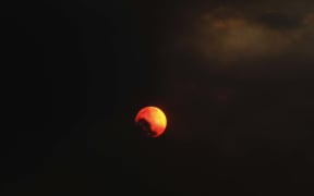 The sun partially disappears behind the black smoke from the Nelson fire.