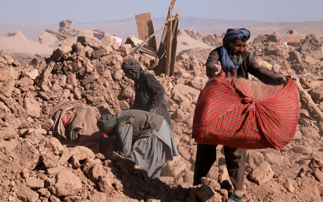 Afghan residents clear debris of damaged houses after earthquake in Nayeb Rafi village, Zendeh Jan district of Herat province on October 10, 2023. Rescue workers scrabbled through rubble on October 10, for villagers buried in their homes by a series of earthquakes that killed more than 2,000 people in rural western Afghanistan, but hope of finding survivors was fading fast. (Photo by Mohsen KARIMI / AFP)