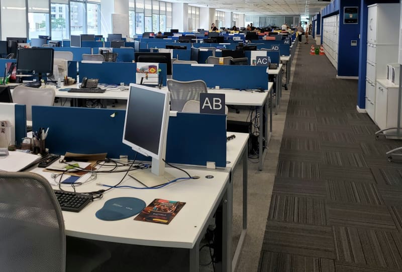 An open office plan with computers and items on desks in rows.