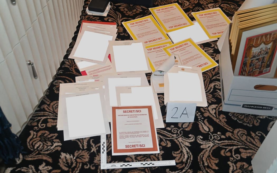 A photo attached as evidence to a court filing by the US District Court Southern District of Florida, of documents allegedly seized at Mar-a-Lago spread over a carpet.