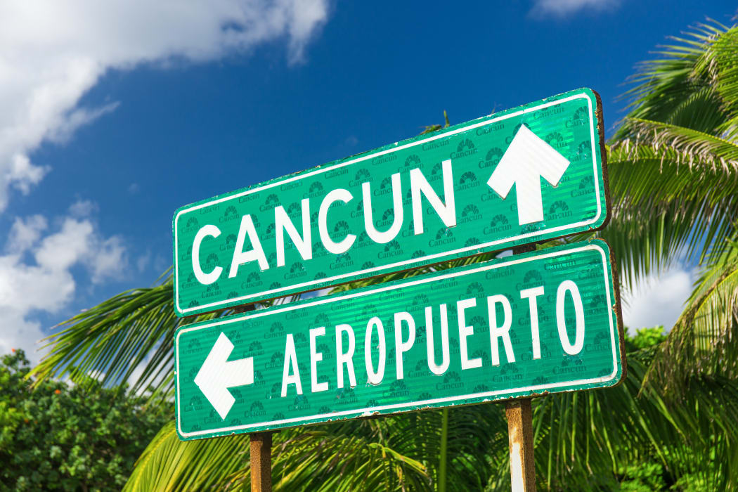 A traffic sign indicating the directions to  Cancun and the airport with arrows in Cancun, Mexico.