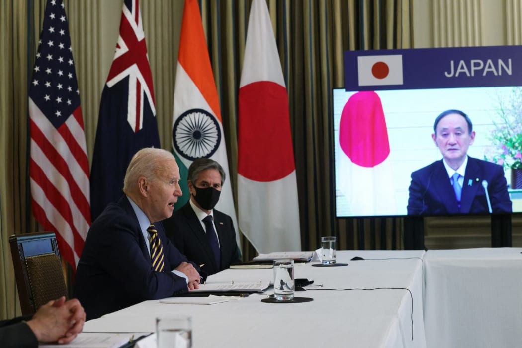 (L-R) U.S. President Joe Biden, U.S. Secretary of State Anthony Blinken and Japanese Prime Minister Yoshihide Suga (on screen) participate in a virtual meeting with leaders of The Quad.