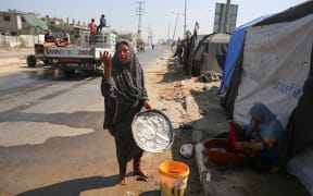 Displaced Palestinians are doing chores by their tents at a makeshift displacement camp set up on a roadside in Deir el-Balah in the central Gaza Strip on August 13, 2024, amid the ongoing conflict between Israel and the Palestinian Hamas movement. (Photo by Majdi Fathi/NurPhoto) (Photo by MAJDI FATHI / NurPhoto / NurPhoto via AFP)