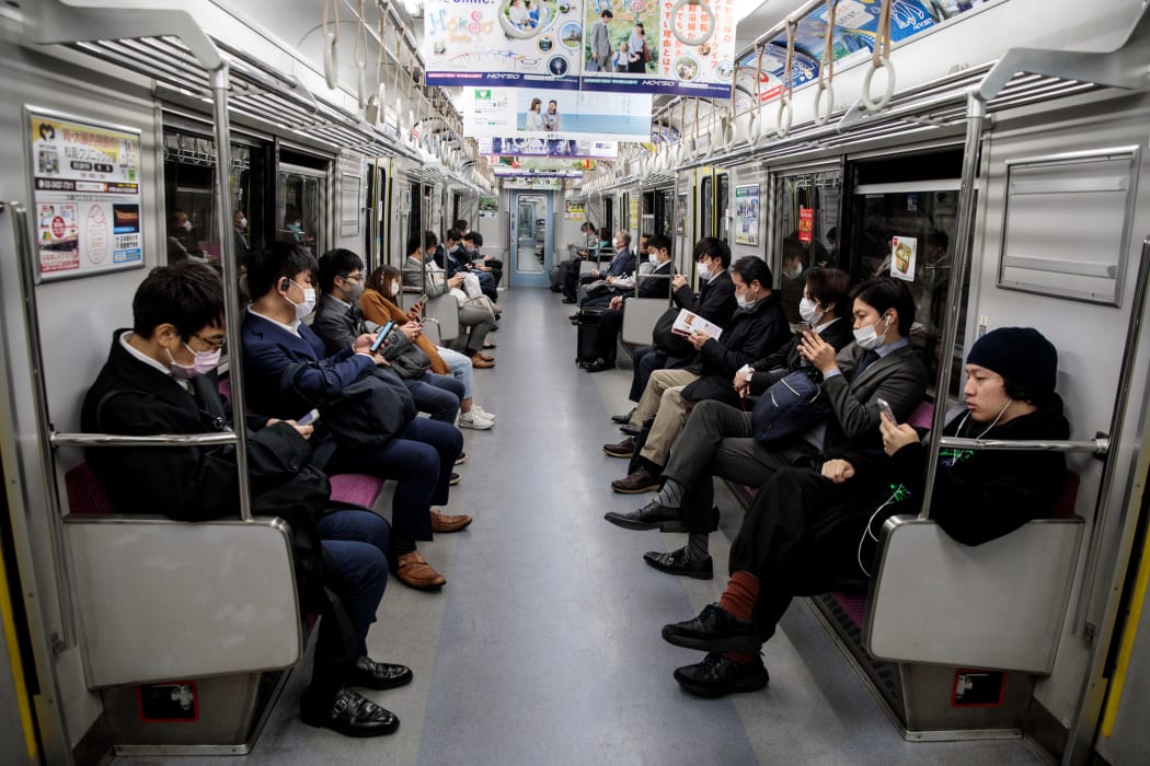 People wearing face masks amid concerns over the spread of the Covid-19 coronavirus, commute on a train in Tokyo on 6 April 2020.
