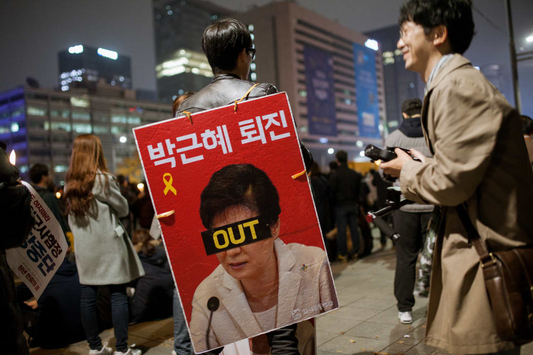 A protester in Seoul holds a sign calling for the resignation of President Park Geun-hye.