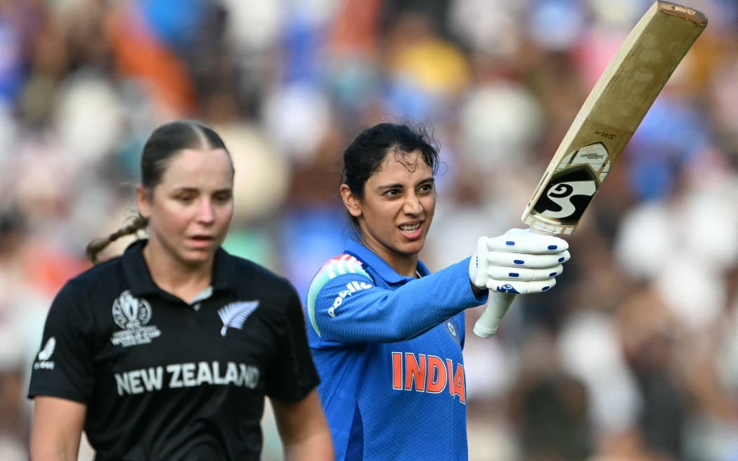 India's Smriti Mandhana (R) celebrates after scoring a century against New Zealand off the bowling of Jess Kerr.
