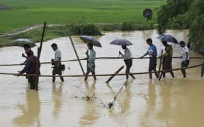 Rohingya Muslim refugees cross floodwater in Thyangkhali refugee camp near the Bangladesh town of Ukhia on September 17, 2017.