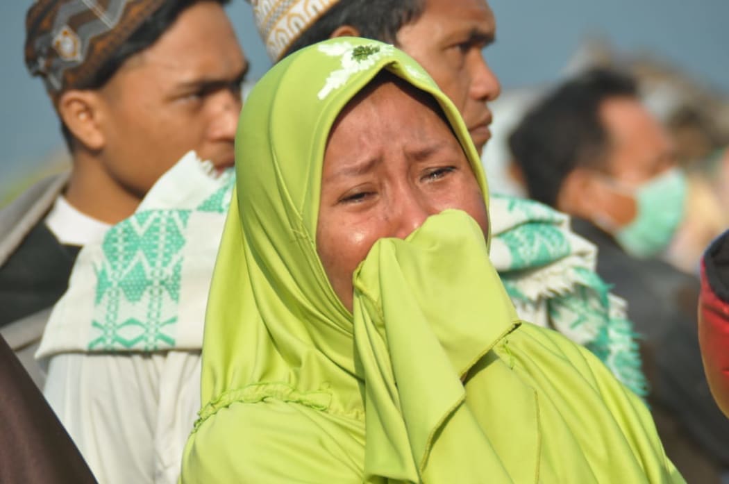 A woman cries as people look at the damages after an earthquake and a tsunami hit Palu, on Sulawesi Island.