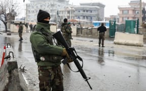 Afghan security personnel stand guard an area following a suicide attack near the Marshal Fahim Military Academy base in Kabul.