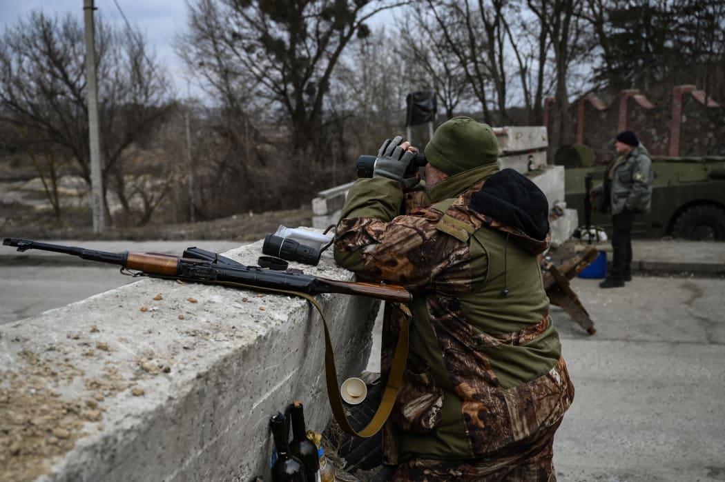 An Ukrainian serviceman looks through binoculars towards the town of Stoyanka at a checkpoint before the last bridge on the road that connects Stoyanka with Kyiv, on 6 March, 2022.