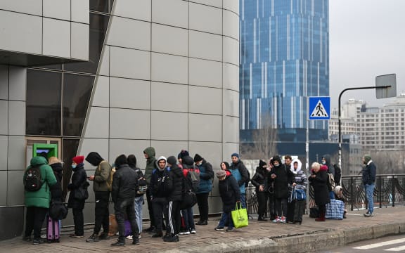 People line up to withdraw money at a cash dispenser in Kyiv in the morning of February 24, 2022.