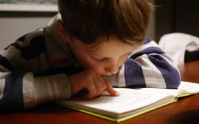 Child reading a book using their finger as a guide