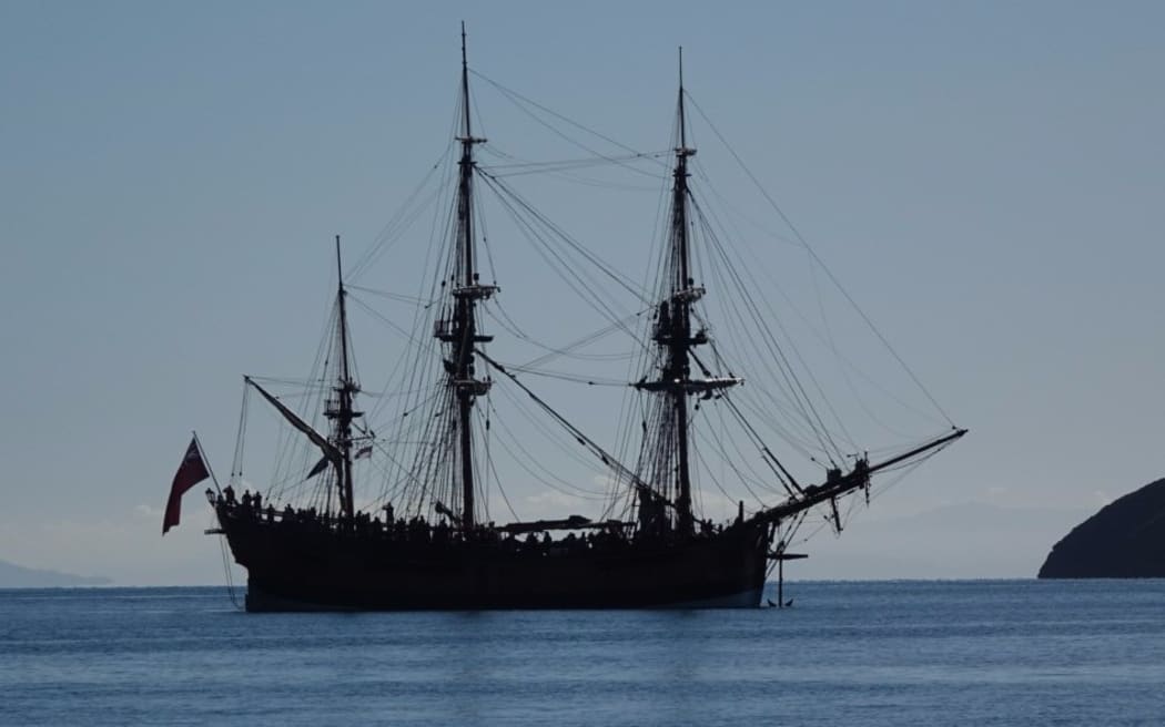 A big three masted sailing ship in the bay.
