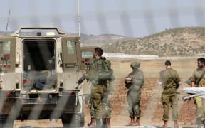 Israeli forces stand during the evacuation of a wounded soldier in the Israeli town of Muqeibila, north of the occupied West Bank, on July 3, 2023. Israel has stepped up operations in the northern West Bank, home to Jenin city and its adjacent refugee camp, a stronghold of Palestinian armed groups where there has been a spate of attacks on Israelis as well as attacks by Jewish settlers on Palestinian communities. (Photo by Menahem KAHANA / AFP)