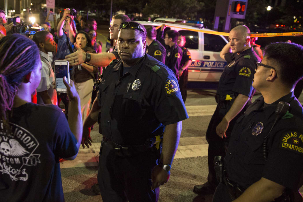 Police attempt to calm the crowd as someone is arrested following the sniper shooting.