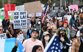 Protesters hold up signs as they gather to demonstrate against federal immigration operations at Pershing Square in downtown Los Angeles, on June 11, 2025. Protests against Donald Trump's harsh immigration policies spread on June 11 across the United States despite a military-backed crackdown in Los Angeles and threats by the hard-right Republican president to use "heavy force." In Los Angeles, where the unrest began on June 6, an overnight curfew intended to keep people out of the downtown area was largely effective, with police arresting around 25 people who had refused to leave. (Photo by RONALDO SCHEMIDT / AFP)