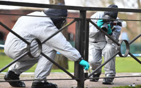 Personel take photographs as they swab railings near a bench covered in a protective tent at The Maltings shopping centre in Salisbury, southern England, on March 16, 2018.