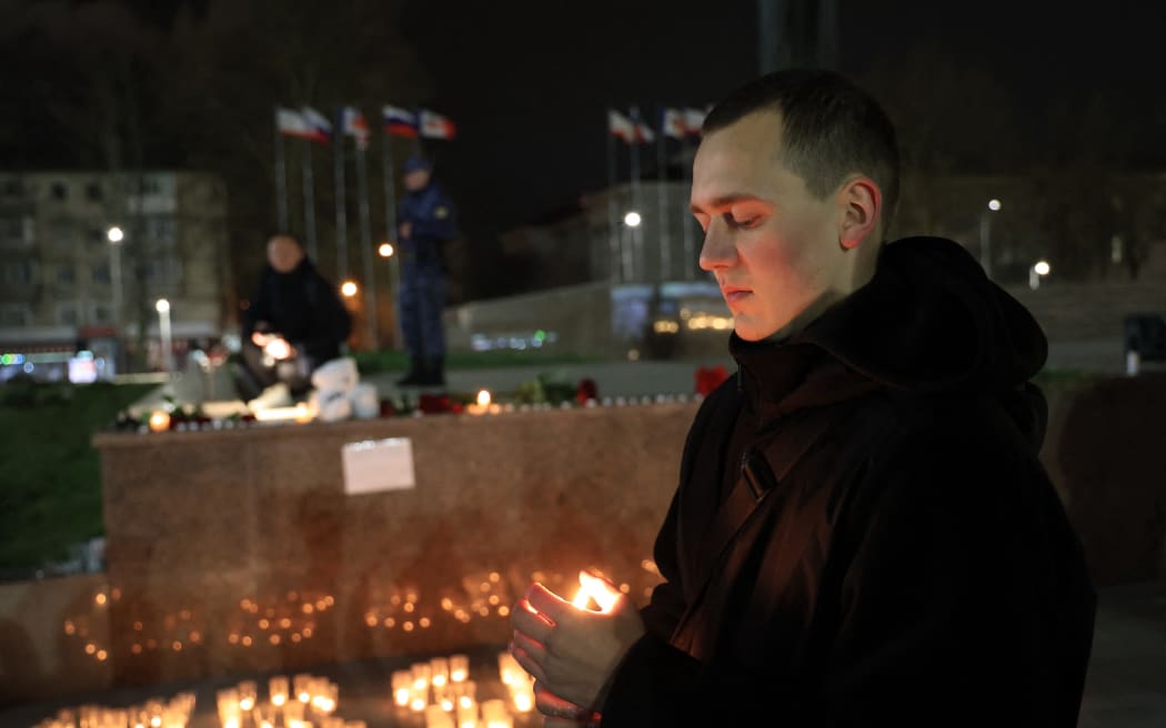 People lay flowers and lit candles in memory of the Moscow concert gun attack victims in the center of Simferopol, Crimea, on March 22, 2024. Gunmen opened fire at a Moscow concert hall on March 22, 2024 killing at least 40 people, wounding more than 100 and sparking an inferno, authorities said, with the Islamic State group claiming responsibility. (Photo by STRINGER / AFP)