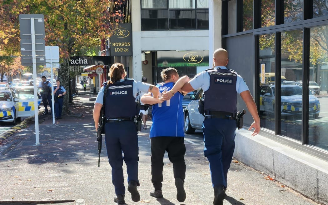 A man being led away by police in handcuffs after reports of a firearm in central Auckland.