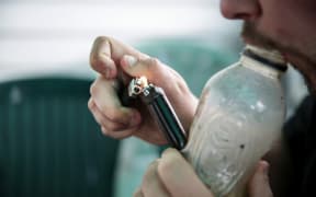 A male smoking using a homemade bong.
