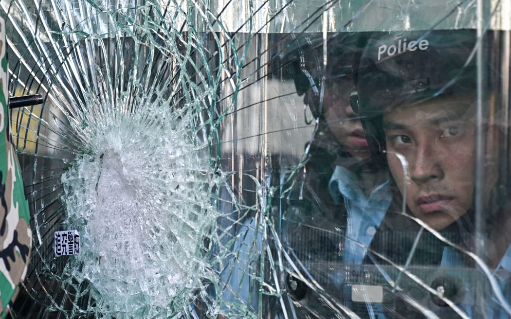 Police standing inside the government headquarters look at protesters who are trying to smash their way into the building in Hong Kong.