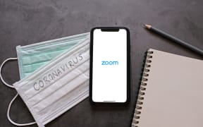 :Flat lay of smartphone showing zoom application and mask with notebook.