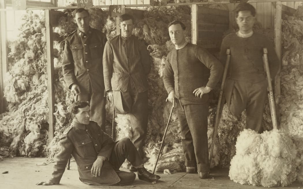 WW1 soldiers posing in front of piles of sheep fleeces at Oatlands Park, Surrey, England.