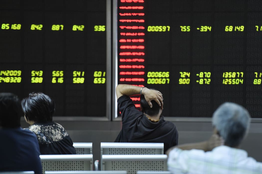 Investors look at screens showing stock market movements at a securities company in Beijing.