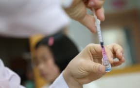 A Chinese medical worker fills up an injector with a dose of vaccine.