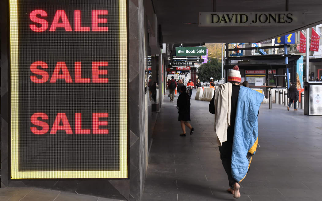 A homeless man walks past a store window in Melbourne's central business district.