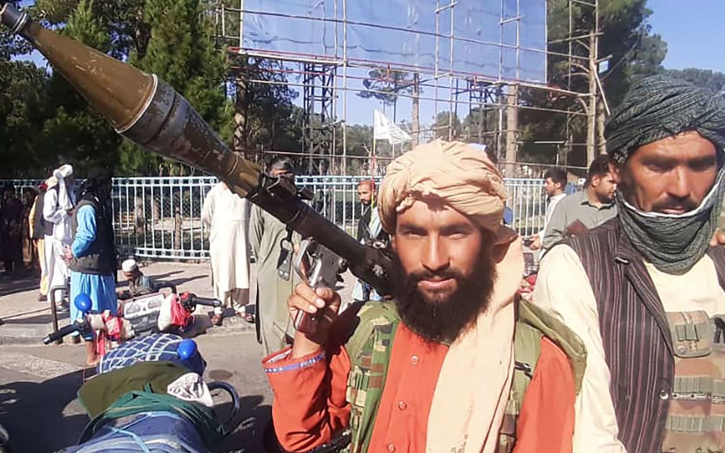 A Taliban fighter holds a rocket-propelled grenade (RPG) along the roadside in Herat, Afghanistan's third biggest city, after government forces pulled out the day before following weeks of being under siege. (Photo by - / AFP)