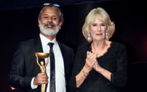 Sri Lankan writer Shehan Karunatilaka (L) poses next to Britain's Camilla, Queen Consort (R) after winning the British Booker Prize for his novel 'The Seven Moons of Maali Almeida', during the Booker Prize for Fiction 2022 awards ceremony, in London, on 17 October 17, 2022.